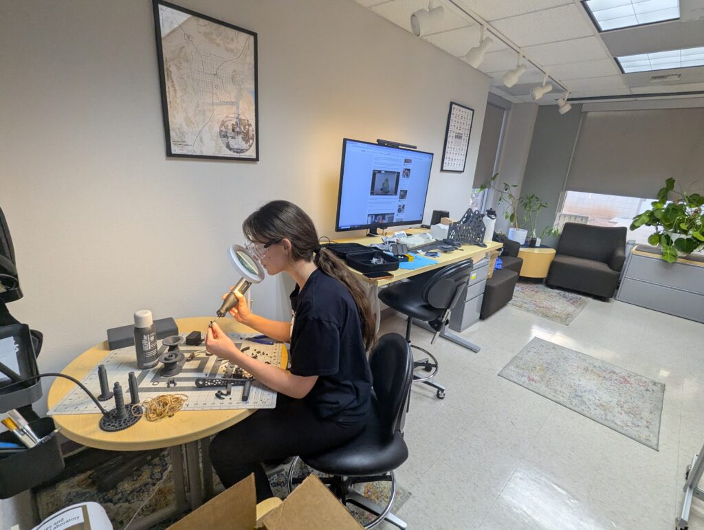 Long hair student working with rotary tools on a circular table. Student is wearing protective goggles.
